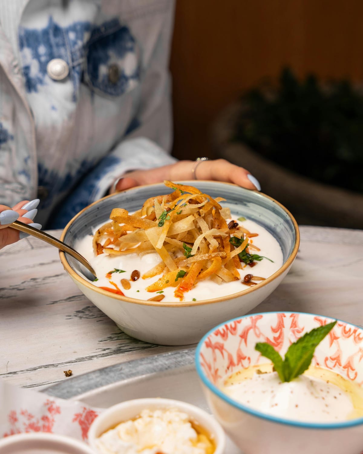 Bowl of Persian mast-o-khiar yogurt dip topped with crispy fried onion strips and pine nuts