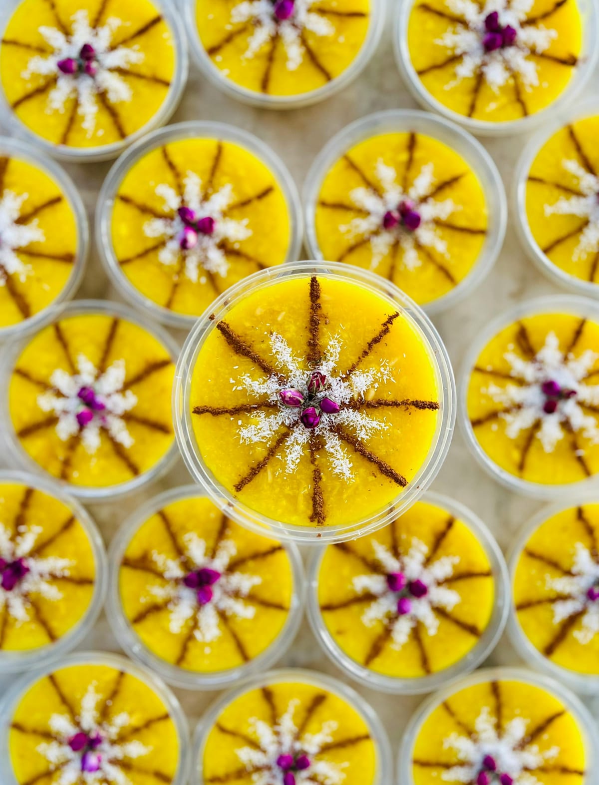 Persian sholeh zard dessert cups arranged for a dinner party, garnished with rose and cinnamon