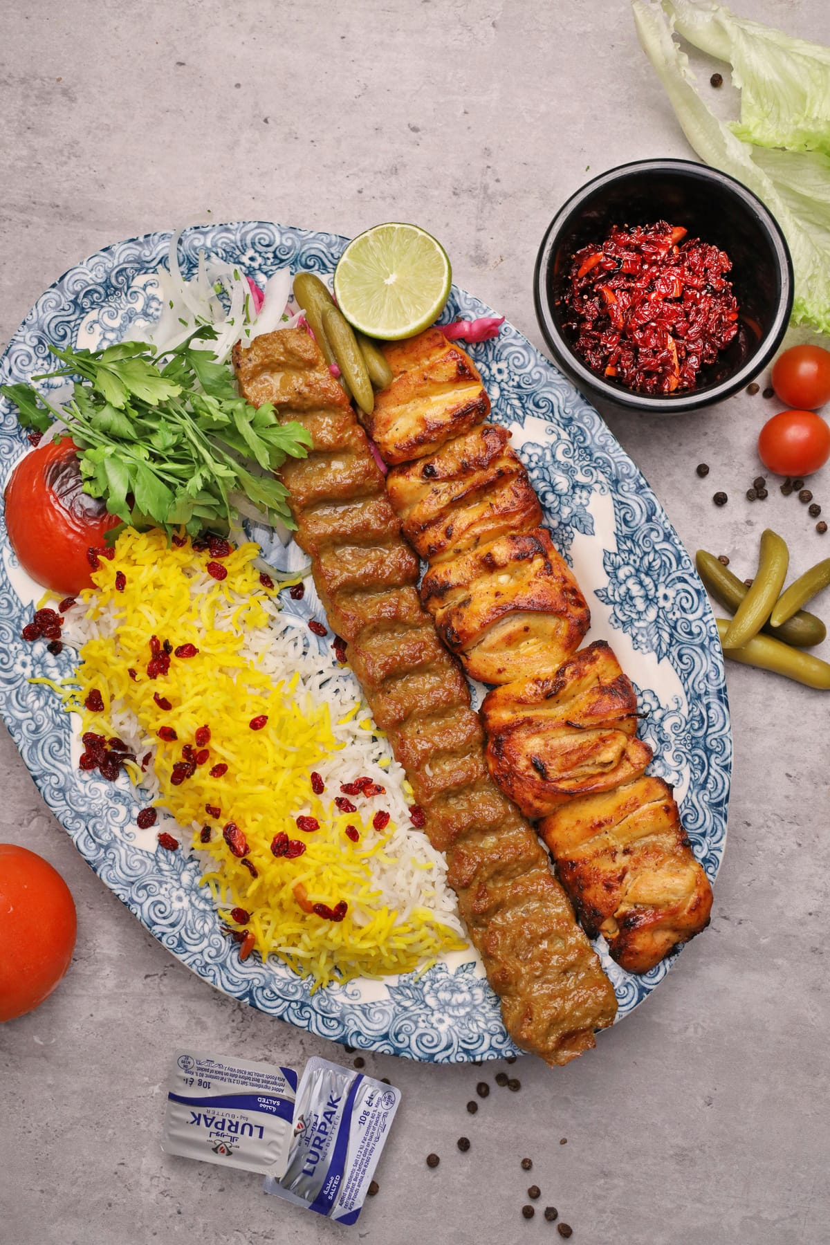Persian Zereshk Polo barberry saffron rice with Koobideh and Joojeh chicken kabab on a blue patterned plate