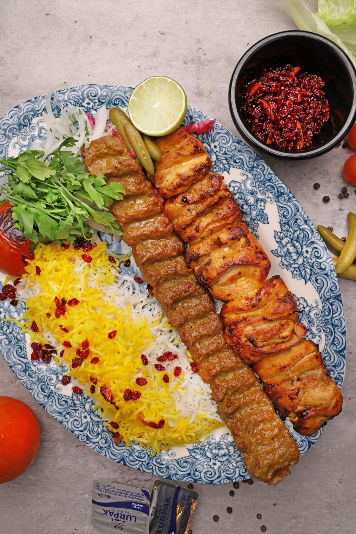 Persian kabab feast on a patterned platter with rice, herbs, lime and condiments