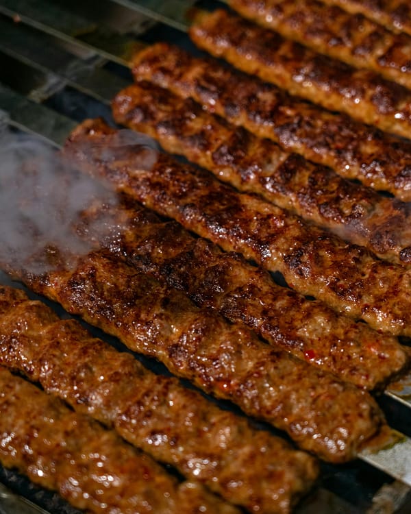 Close-up of spicy regional-style kababs grilling on flat Persian skewers
