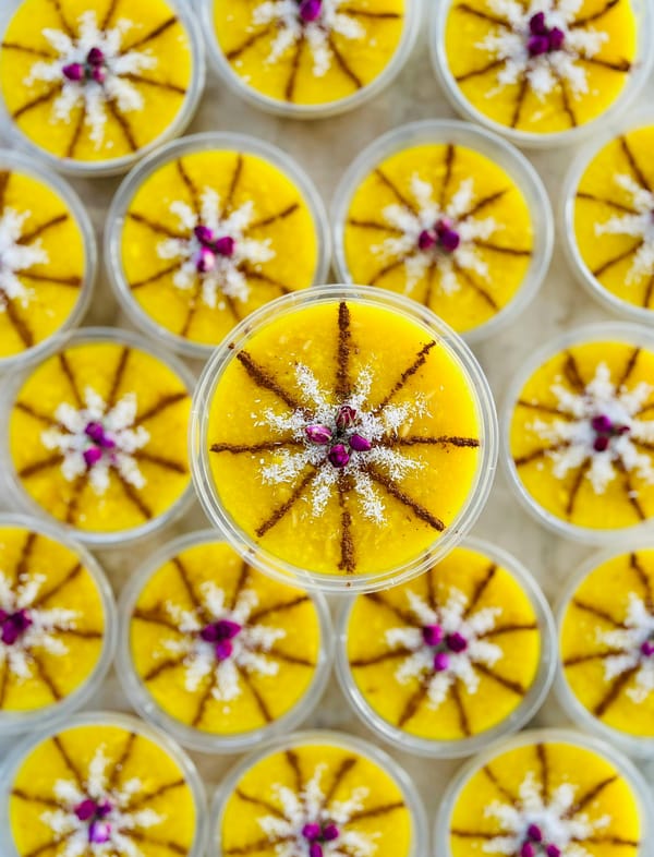 Persian sholeh zard dessert cups arranged for a dinner party, garnished with rose and cinnamon